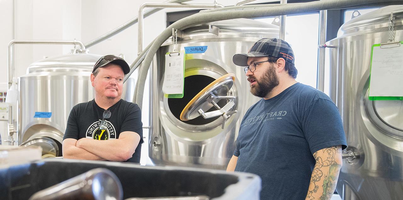 Sean Johnson and Dan Yetters standing and talking in the brewery.