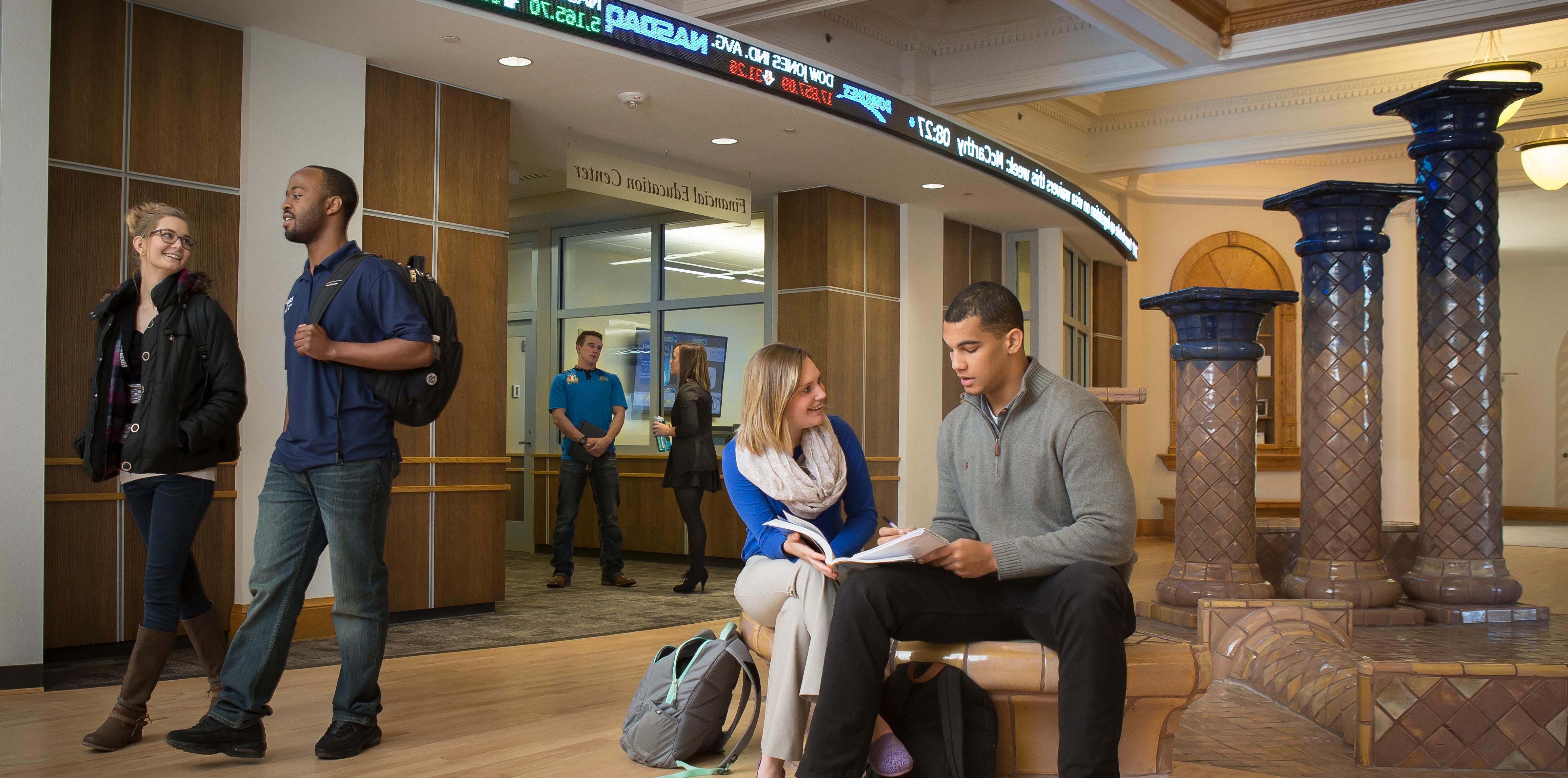 Students sitting inside college building talking to faculty member